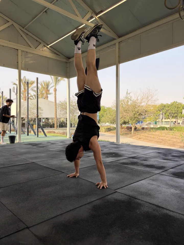 An athlete holding a freestanding handstand on the gym mats.